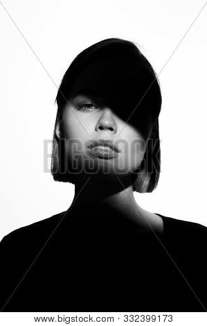 Fashionable Beauty Portrait. Black Silhouette On White Background. Girl With A Spot Of Light On Her 