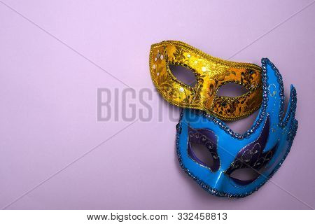 Two Carnival Masquerade Masks Yellow And Blue On A Lilac Background Copy Space