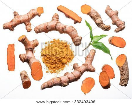Fresh turmeric rhizome cuts and turmeric powder isolated on white background.