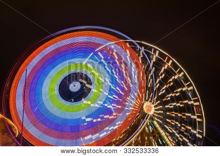 Two Rides In Motion In Amusement Park, Night Illumination. Long Exposure.
