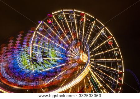 Two Rides In Motion In Amusement Park, Night Illumination. Long Exposure.
