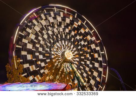 Two Rides In Motion In Amusement Park, Night Illumination. Long Exposure.