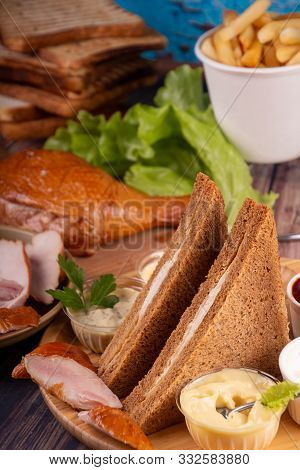 Heep Of Sandwiches Toasted Bread And Smoked Chiсken On Wooden Table. Fast Food Unhealthy Concept.