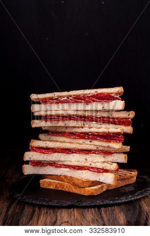 Heep Of Sandwiches Toasted Bread And Salami On Black. Fast Food Unhealthy Concept