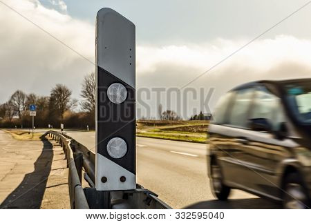 Fast Car Driving Under A Bridge Beside A Reflection Post.