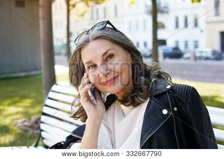 Cheerful Beautiful European Female In Her Fifty Enjoying The Nice Summer Weather Outdoors, Sitting O