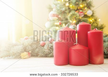 Red Christmas Candles On White Wooden Plank Against Christmas Tree In Living Room