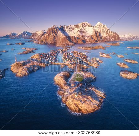 Aerial View Of Rocks In Sea, Snowy Mountains, Purple Sky At Sunset In Lofoten Islands, Norway. Winte