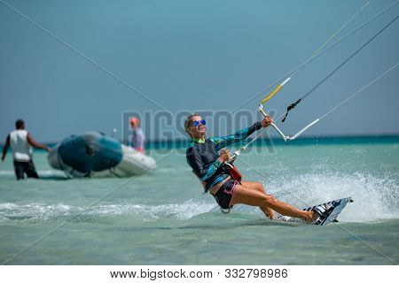 Kite surfing girl in sexy swimsuit with blue kite. Recreational activity, water sports, action, hobby and fun in summer time. 