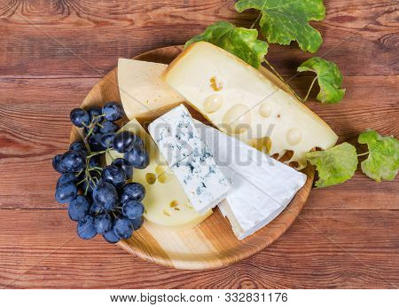 Various Cheese With White And Blue Mold, Medium-hard Cheese And Swiss-type Cheese, Blue Grapes On Th