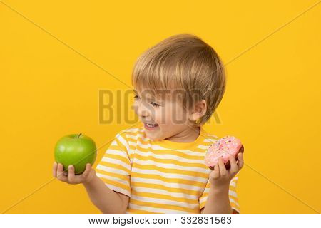 Happy Child Holding Donut And Apple
