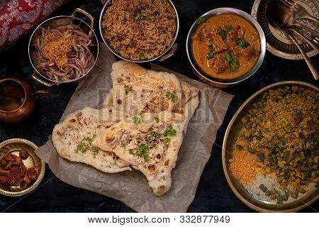 Indian Naan, Korma, Pilaf And Side Dishes On Dark Background