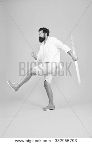 Knowledge In Brutal World. Brutal Hipster Walking With Ruler On Yellow Background. Bearded Man With 