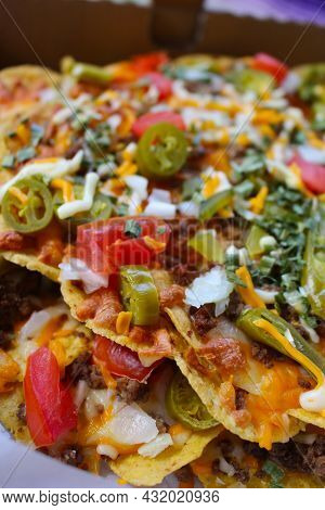 Take Out Box With Nachos Topped With Beef, Jalapenos,tomatoes, Onions And Cheese, With Salsa And Sou