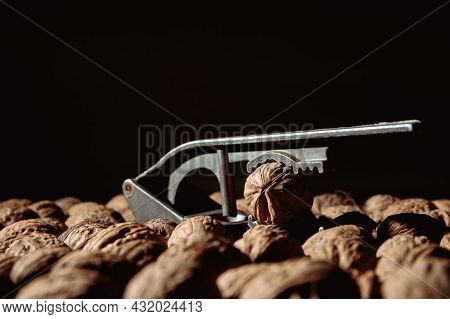 Walnut In A Nutcracker Close-up. Dark Background. Beautiful Background With Food. Healthy Ingredient