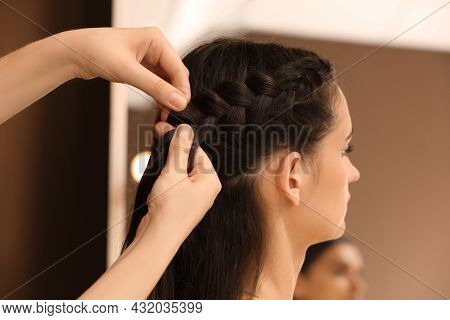 Professional Stylist Braiding Client's Hair In Salon
