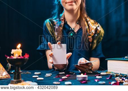 Magic And Esotirism Concept. Smiling Fortune-teller Shows An Empty White Tarot Card. Cartomancy And 