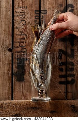 Male Hand Taking Out Air-dried Salted Sabrefish From Glass