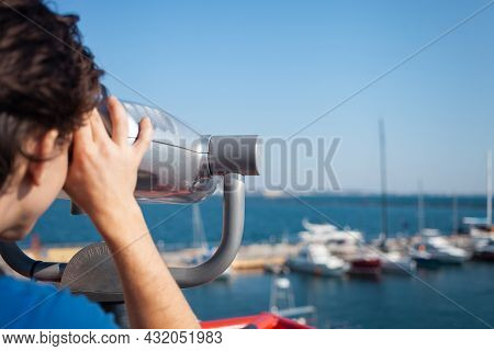 Man Looks Through Stationary Binoculars. Binoscope On Observation Deck Near Sea. Seaport In Odessa. 