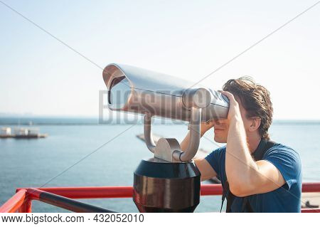 Man Looks Through Stationary Binoculars. Binoscope On Observation Deck Near Sea. Seaport In Odessa. 