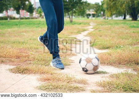 Old Soccer Ball With Teenager Feet On The Football Field. Selective Focus.