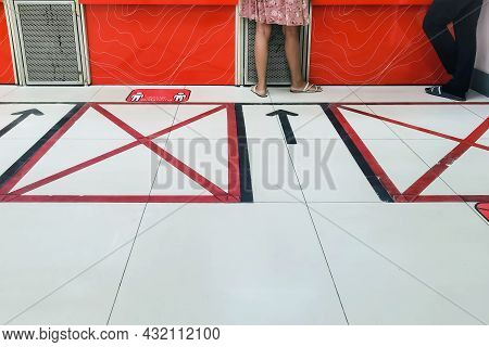 Feet Of Male And Female Customers Waiting To Deliver Parcels With Customer Floor Sign, Warning To St