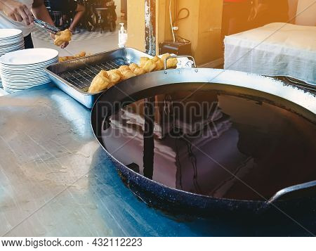 Dough Sticks Or Deep-fried Chinese Dough Called Patongo For Sale On Tray Near Large Frying Pan. Pato