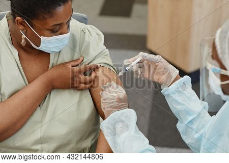 Serious African-american Woman In Medical Mask Looking At Nurse Getting Shot Of Vaccine Against Covi