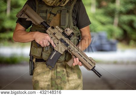 Close Up Of A Man Standing With An Airsoft Assault Rifle In Military Uniform