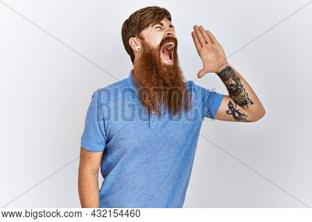 Caucasian man with long bear standing over isolated background shouting and screaming loud to side with hand on mouth. communication concept. 