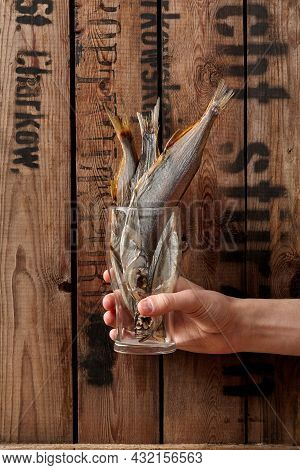 Male Hand Holding Glass With Air-dried Salted Sabrefish