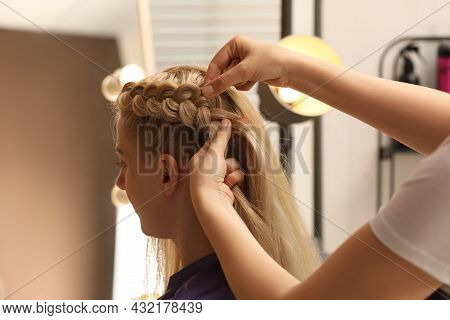 Professional Stylist Braiding Client's Hair In Salon