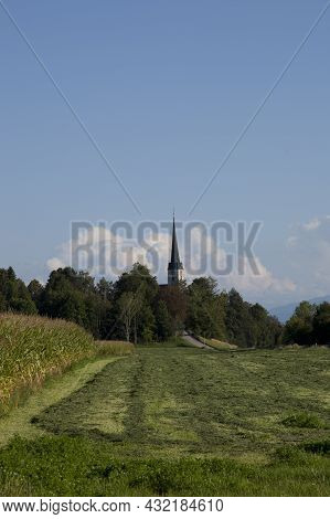 The High Spire Of The Church Of St. George With A Cross In The Village Of San Georgien In Germany
