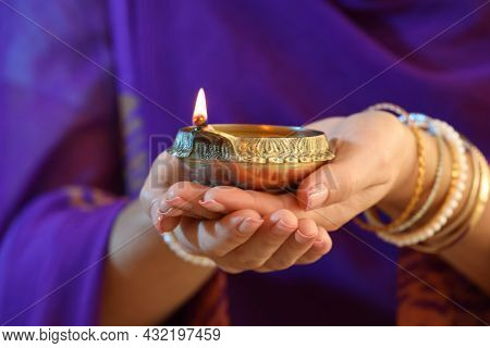 Woman Holding Lit Diya Lamp In Hands, Closeup. Diwali Celebration