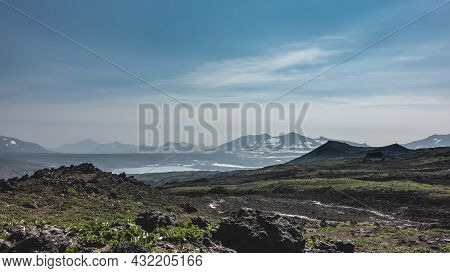 Scant Vegetation And Volcanic Rocks Are Visible On The Mountain Slope. In The Distance, You Can See 