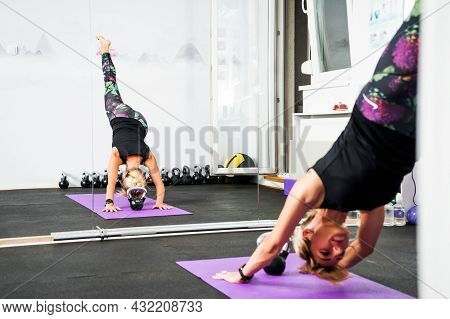 Adult Woman Is Practicing Yoga In Gym. Eka Pada Adho Mukha Svanasana/one-legged Downward-facing Dog 