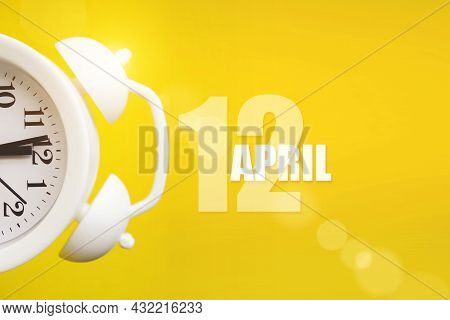 April 12nd. Day 12 Of Month, Calendar Date. White Alarm Clock On Yellow Background With Calendar Day