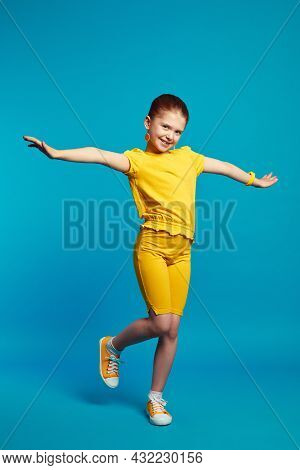 Vertical Full Body Shot Of Cute Little Girl In Yellow Outfit Smiling And Dancing In Studio, Isolated