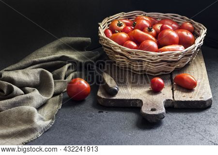 Fresh Red Tomatoes In Whicker Basket On Black Background.