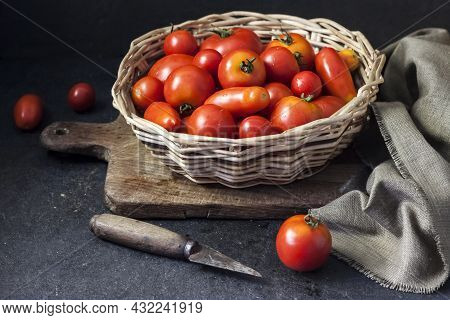 Fresh Red Tomatoes In Whicker Basket On Black Background.