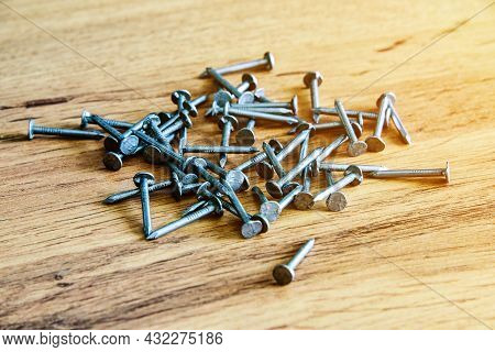 Heap Of Thin Metal Nails Close Up On Wooden Surface.
