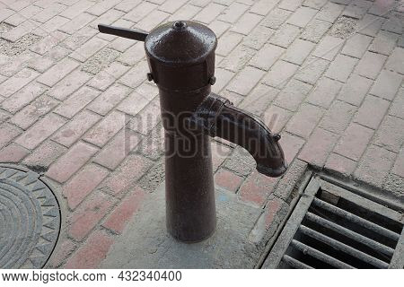 One Big Old Brown Iron Pump In The Pump Room For Pumping Water On The Sidewalk By The Metal Grate