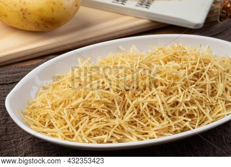 Potato Straw Or Shoestring Potato In A White Plate With Raw Potatoes.