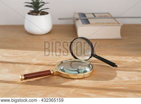 Magnifying Lenses On Wood Desk With Book. Concept Of Exploration, Study And Research.
