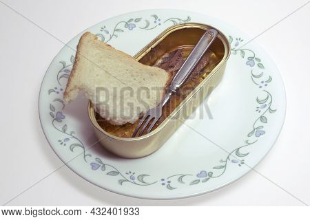 Canned Fish, Sardines In Oil, And Small Metal Fork With Three Prongs. Open Tin Can Without Lid And A