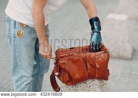 Young Disabled Man Hold And Zips Backback Leather Bag With Artificial Prosthetic Hand In Casual Clot