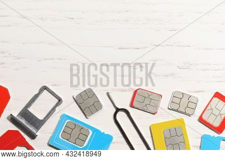 Different Sim Cards, Ejector And Tray On  White Wooden Background, Flat Lay. Space For Text