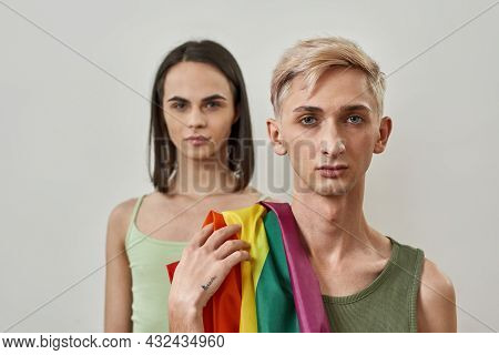 Portrait Of Young Transgender Couple With Flag Of Lgbt Posing Together Isolated Over Light Backgroun