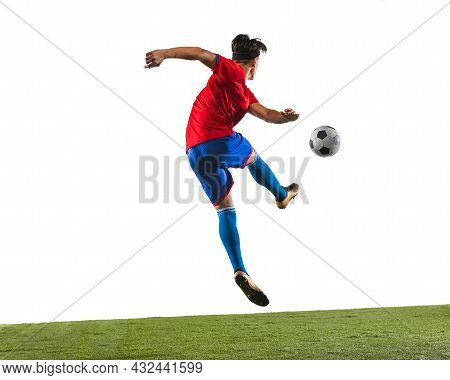 Full-length Horizontal Portrait Of One Male Soccer Football Player Kincking A Ball On Grass Flooring