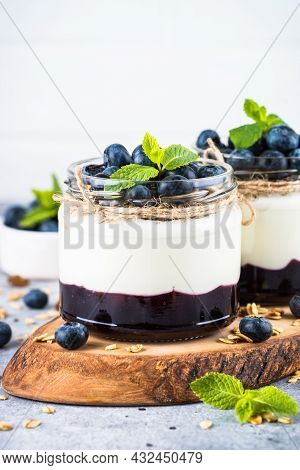 Parfait With Blueberry, Granola And Jam In Two Glass Jars.